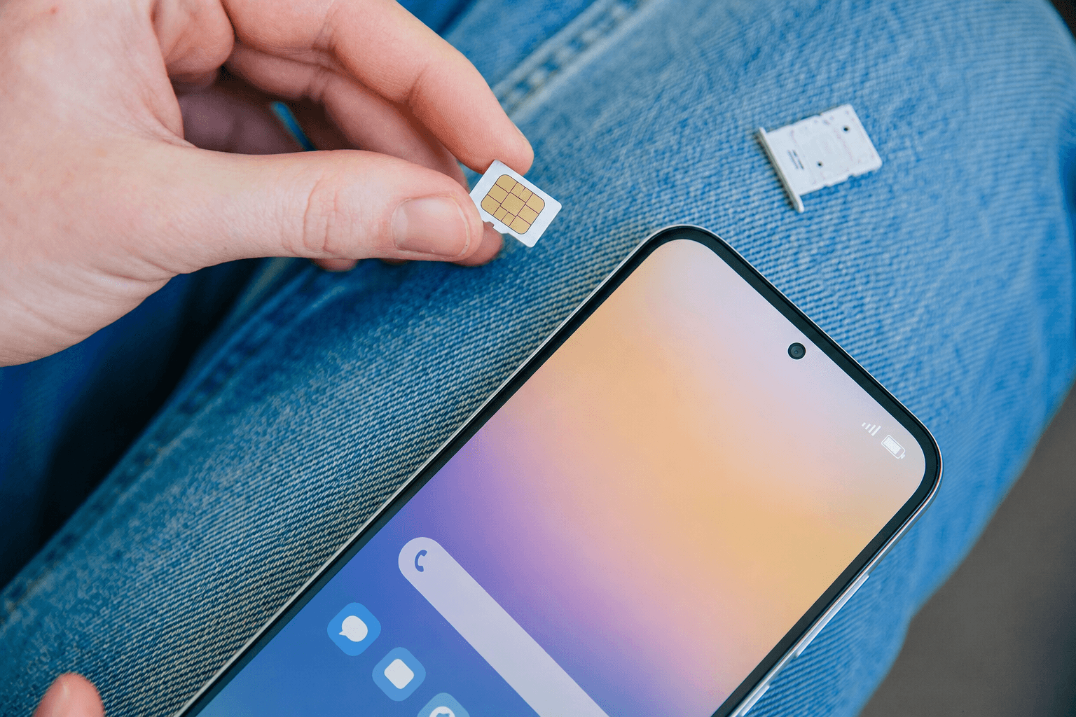Hand inserting a SIM card into a smartphone — get connected with AllNetworks